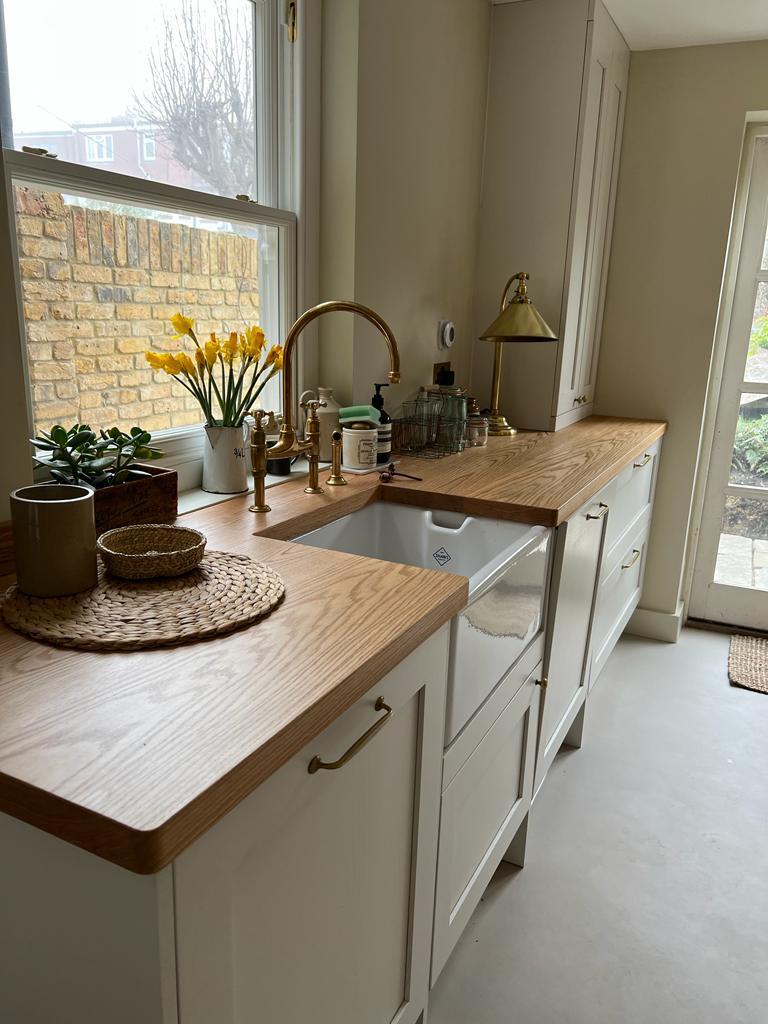 Ivory shaker kitchen with solid oak worktop, Belfast sink and brass bridge tap under a sash window, Clairville Gardens Hanwell W7