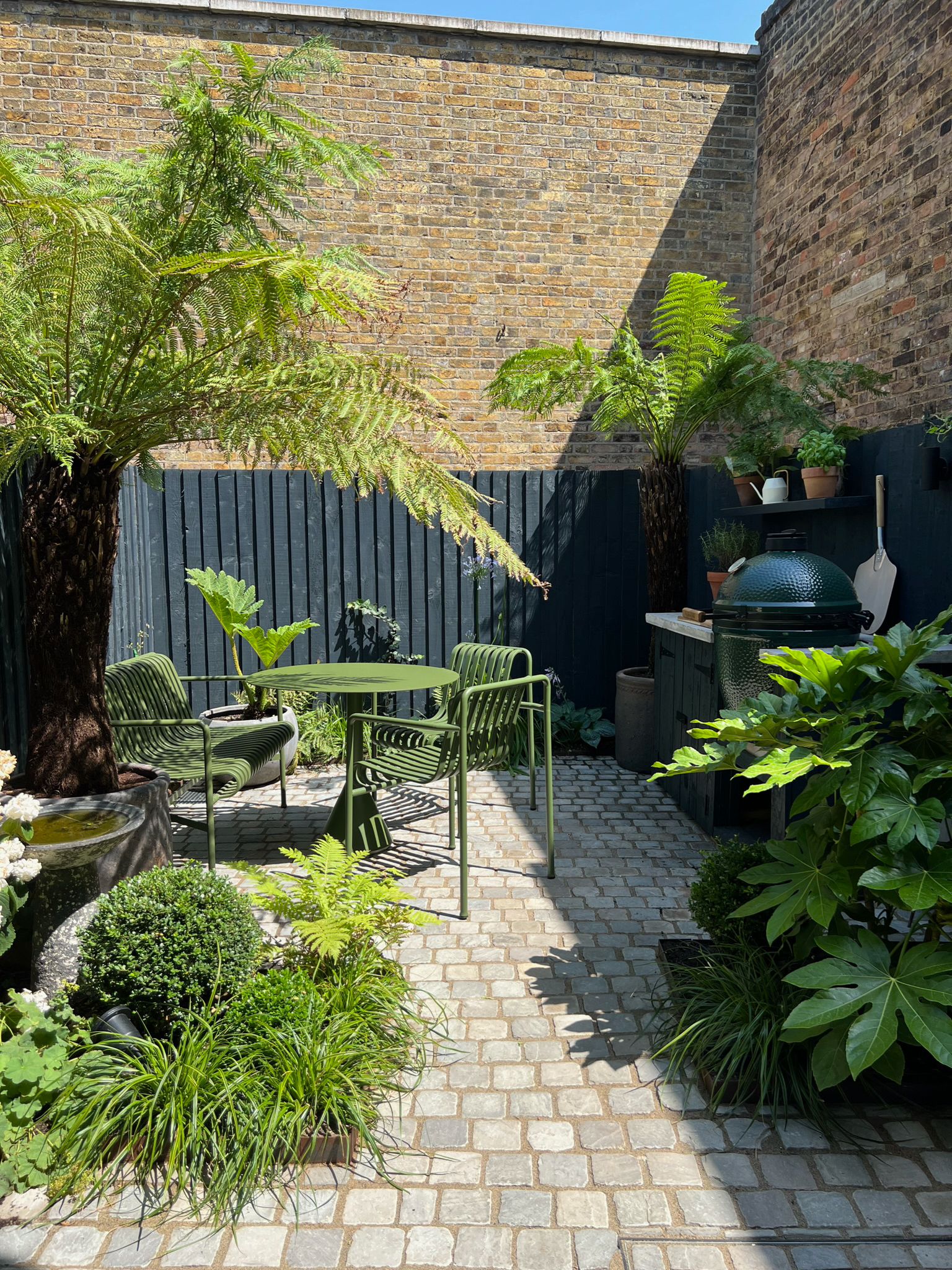 Landscaped garden with paving, ferns and seating behind a Victorian house, Clairville Gardens W7