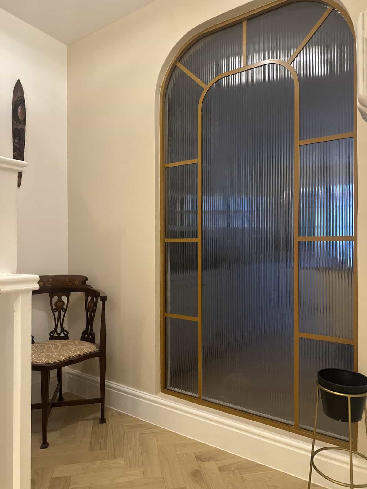 Arched glazed screen with brass frame and reeded glass in a hallway, Hanover Place E3