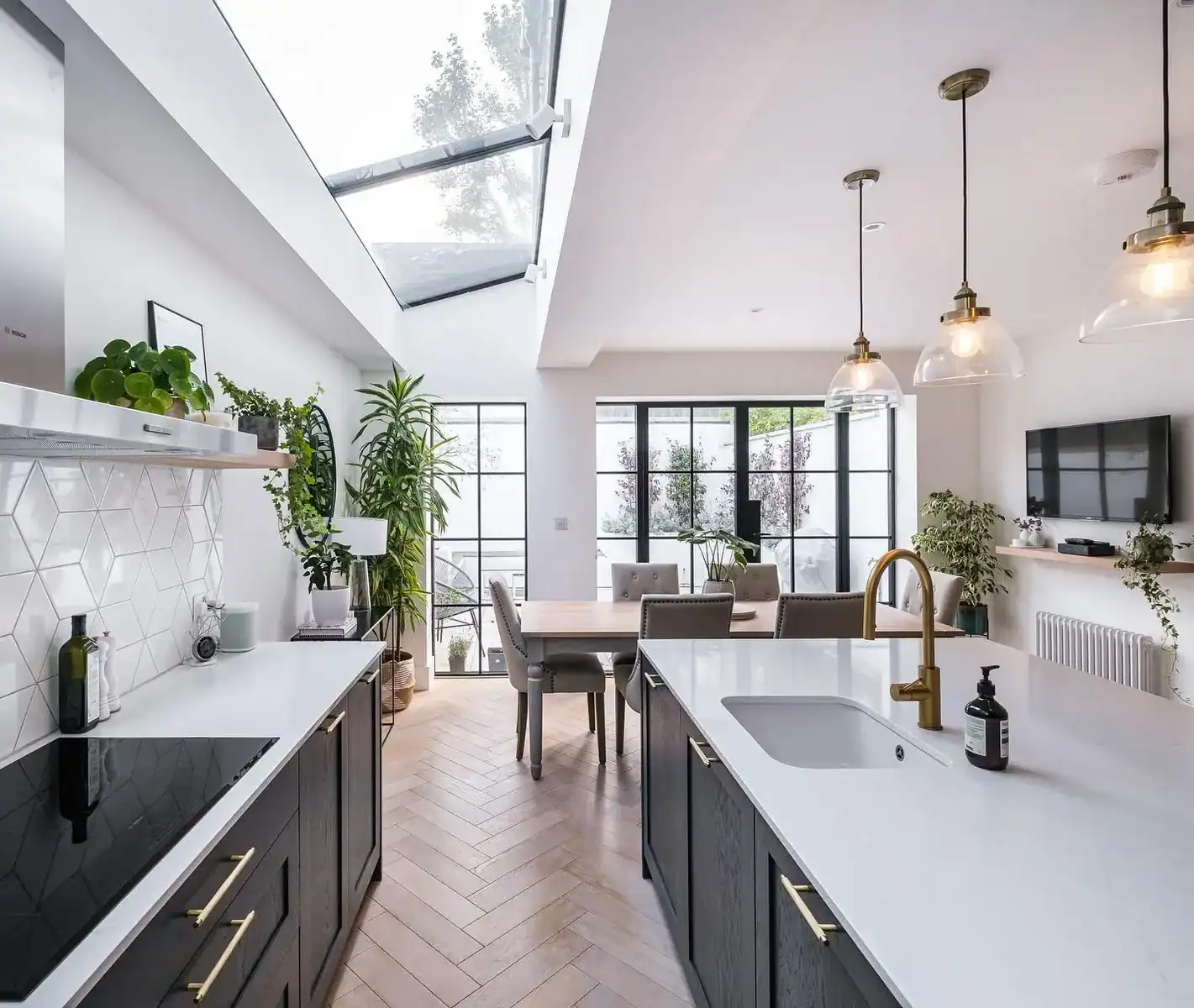 Glazed side return roof over a navy kitchen with white worktops and herringbone floor, NW11 extension