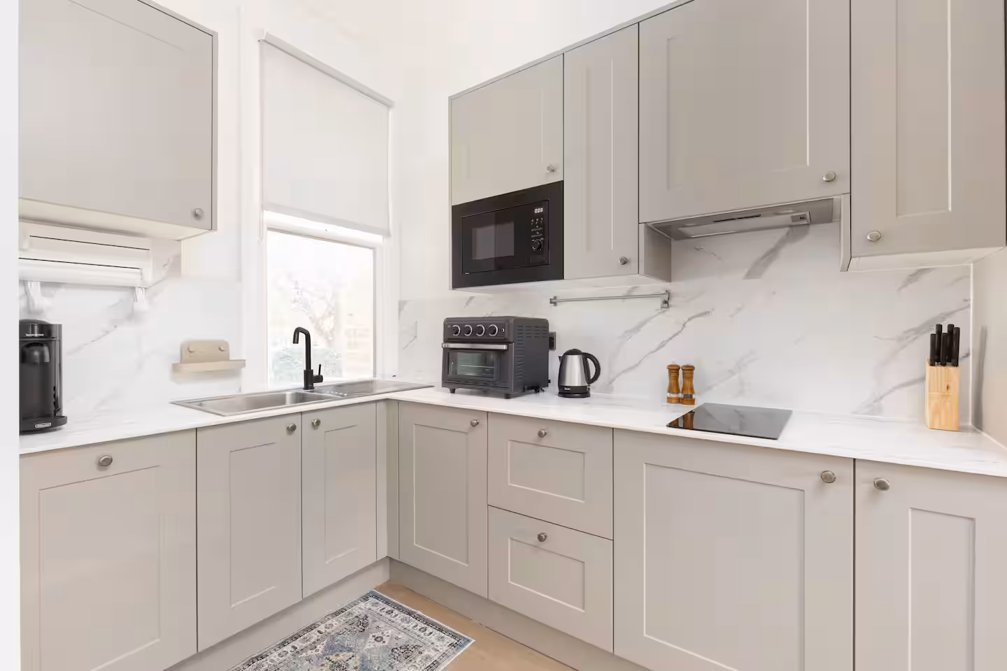 Corner of a shaker kitchen with marble effect splashback and window, St John's Wood
