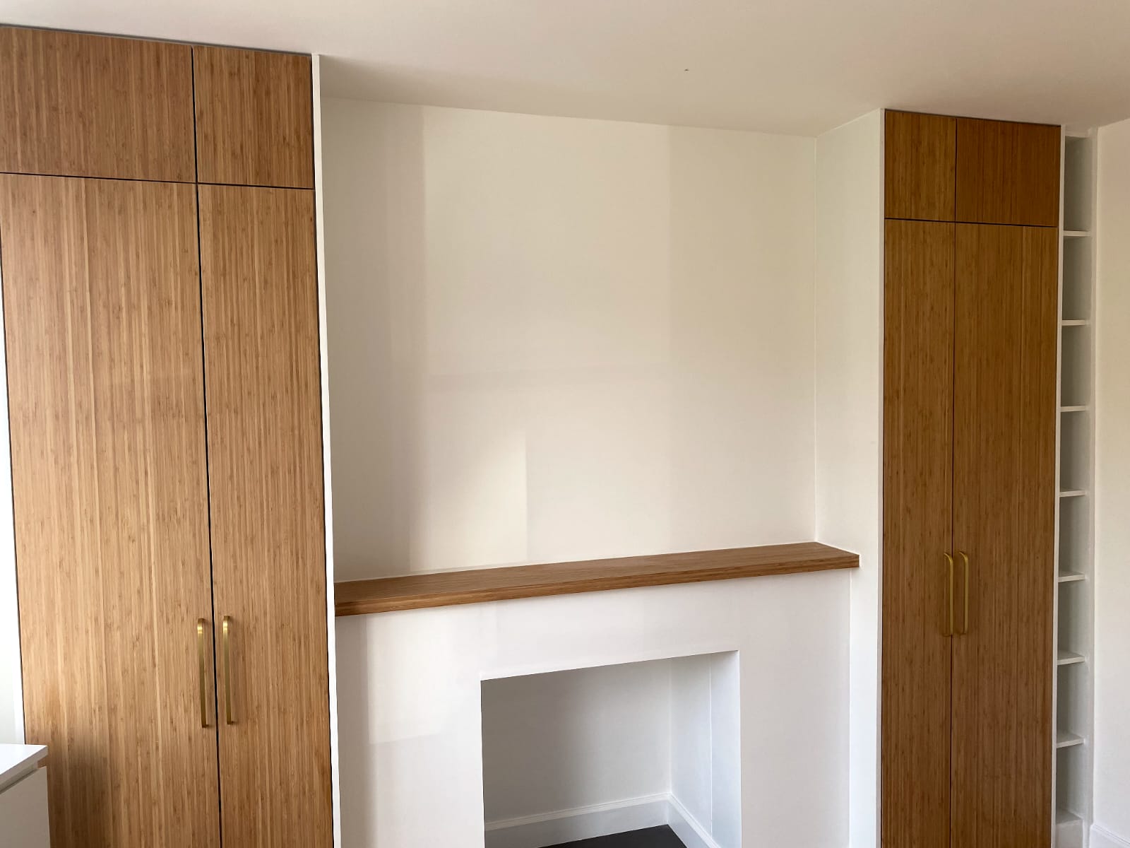 Fitted oak alcove cupboards either side of a chimney breast with floating oak mantel shelf, Staveley Road W4