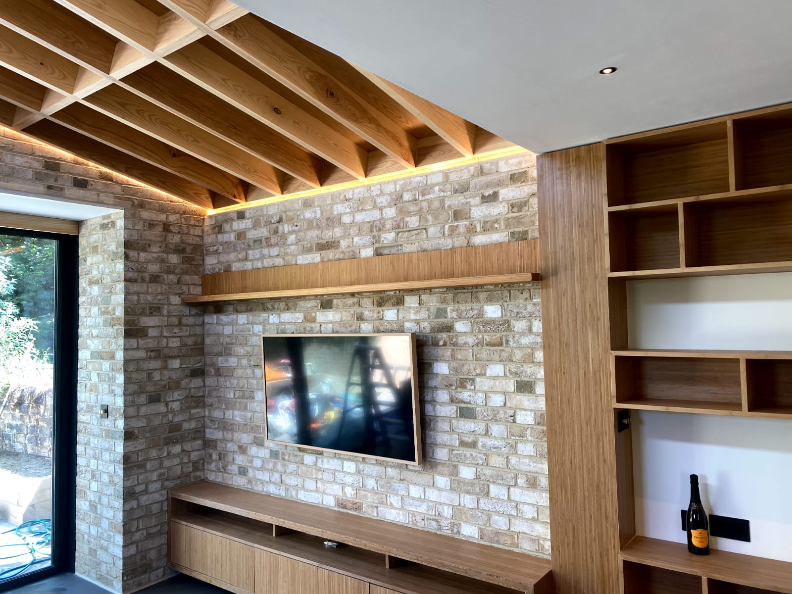 Brick slip media wall with oak TV shelf and timber slatted ceiling with LED lighting, Staveley Road W4