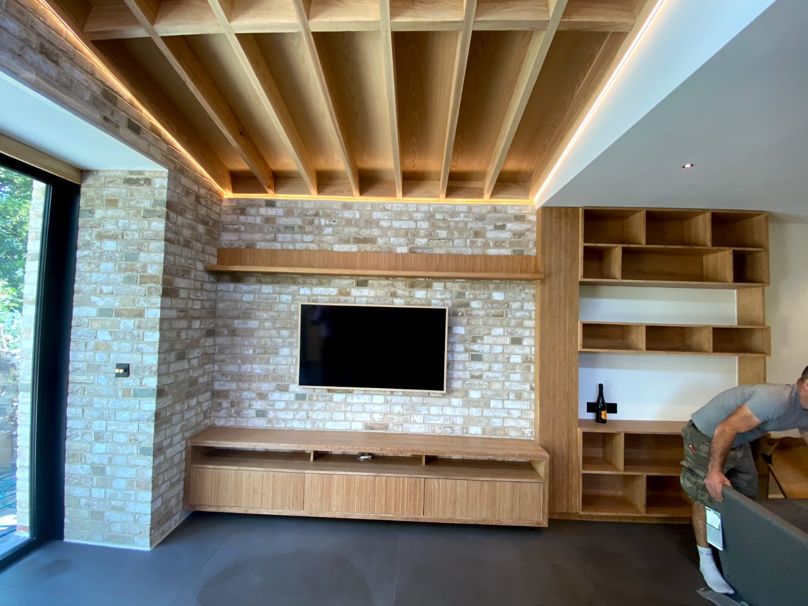 Living room with timber slatted ceiling, brick slip wall and fitted oak shelving unit, Chiswick